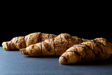 Croissant coffee. Fresh pastry bread or french breakfast croissants with chocolate in bakery on black stone table. Homemade croissants, best for coffee.