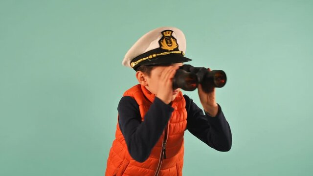 Young seaman captain looks something in the sea. cyan background
