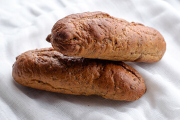 two freshly baked rye bread rolls on a white cloth napkin