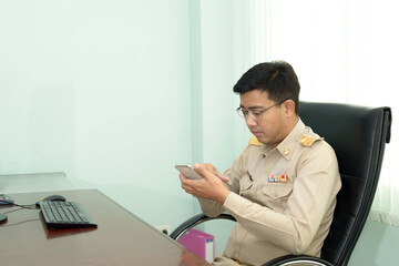 A Thai government officer, Civil servant is using the smartphone at the office.