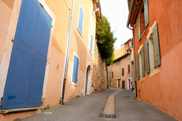 Empty narrow street of the Provencal village. Old houses painted with ocher. Street water drainage....