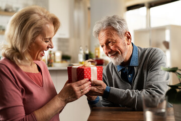 Husband giving a present to his wife. Senior man surprise his beautiful wife..