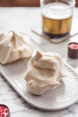 Homemade sweet meringue cookies and cup of coffee on white marble table. Delicious and light dessert. Selective focus