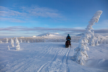 after a big storm, a snowmobiler goes on a journey at dawn, high in the mountains in an unrealistically beautiful place