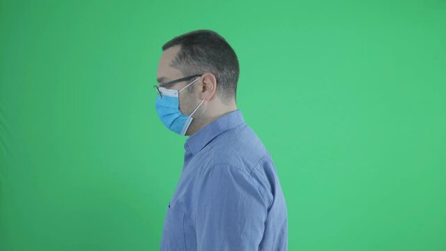 Man with face mask show smartphone for scanning, lateral view isolated on green screen chroma key
