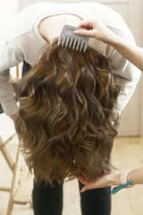 Naklejka premium light brown long curly loose hair closeup photo in hair salon back view