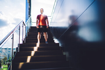 Young sportsman standing on stairs near building