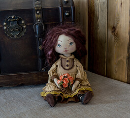 A textile interior doll sits against the background of a vintage chest. Handmade.
