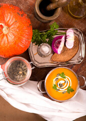 Bowl of pumpkin soup on rustic wooden background