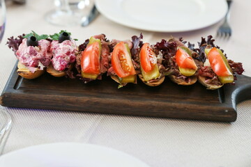 sandwiches are on a board on a served table in a restaurant 