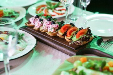 sandwiches are on a board on a served table in a restaurant 