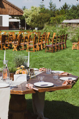 Banquet tables in nature. Wedding in the garden. Outdoor wedding. Buffet. Wedding banquet in nature.
Festive table serving dishes stands on green grass. table compositions, glasses, candles and plates