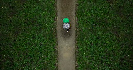 Unrecognizable couple of people going under two umbrella.  top view. wet and dirty land. springtime...