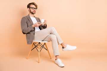 Full size photo of handsome charismatic businessman having break drinking coffee isolated on beige...