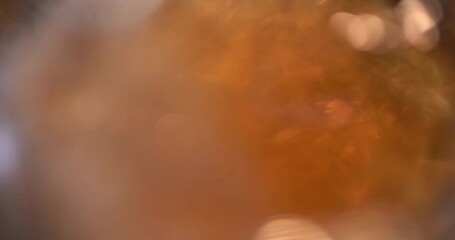 Craft Beer is pouring into angled glass. . Cold Light Beer in a glass with water drops. Craft Beer forming waves close up. Freshness and froth. Bar background. pour beer from the bottle to the last