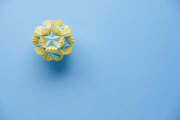 Multicolor handmade modular origami ball or Kusudama Isolated on blue background. Visual art, geometry, art of paper folding, paper crafts. Top view, close up, selective focus, copy space.