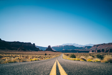 Fototapeta na wymiar Long empty asphalt road with double solid in dry valley in USA