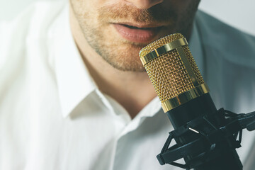 young man recording podcast. speaking in microphone closeup