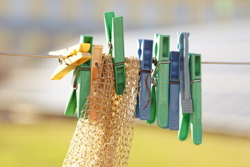 Plastic clothespins hang on a rope with a net in a sunny garden