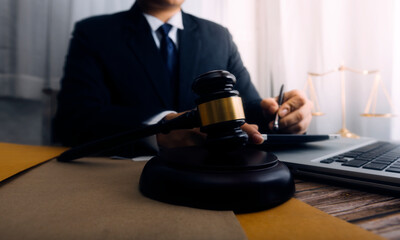 Justice and law concept.Male judge in a courtroom with the gavel, working with, computer and...
