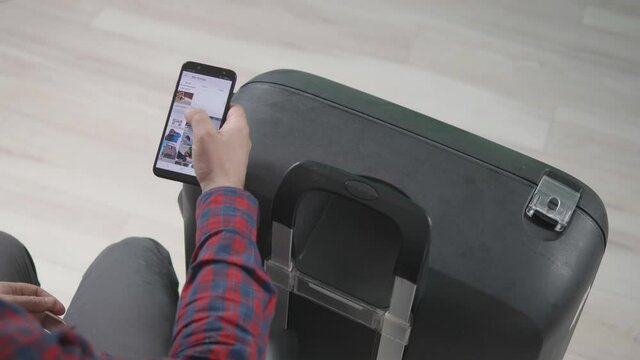 Man with suitcase searches his mobile phone for health digital certificate