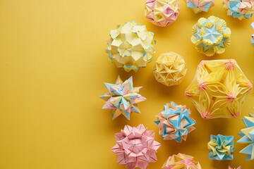 Set of multicolor handmade modular origami balls or Kusudama Isolated on yellow background. Visual...