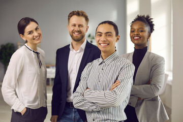 Portrait of young male business leader or executive with team of employees smiling at camera. Happy...