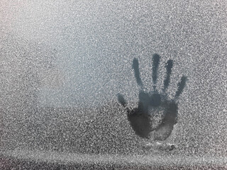 Palm print on the frozen glass. Trace hands and fingers on the window covered with snow frost.