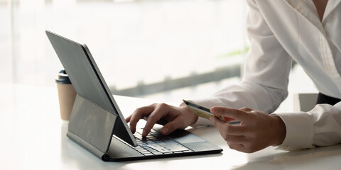 Fototapeta premium Close up girl makes a purchase on the Internet on the digital tablet with credit card at home