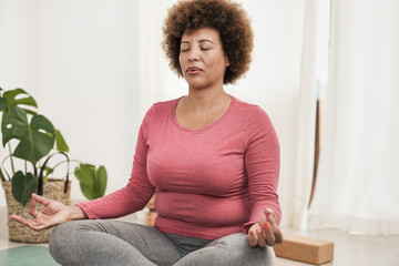 Mature african woman doing yoga meditation inhaling and exhaling - Healthy lifestyle concept