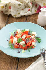goat cheese with fresh tomatoes salad on blue plate on wooden table