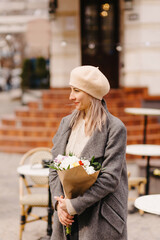 Woman in beret and glasses with a bouquet of flowers