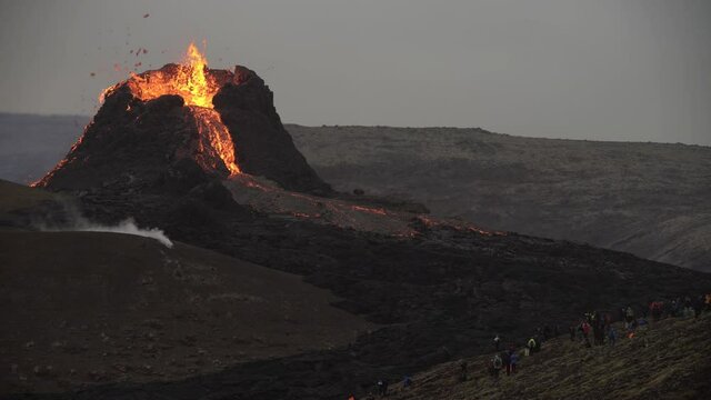 Volcanic eruption Iceland 2021 people under volcano cone and lava field