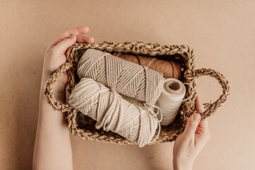 Women's hands holding the basket with cotton yarn. Cotton yarn for macrame in a rectangular basket. - obrazy, fototapety, plakaty
