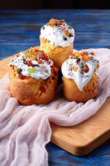 Three delicious freshly baked Easter cakes on blue wooden board with pink gauze