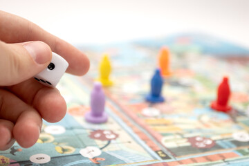 Hand throwing the dice on the board game playing field.
