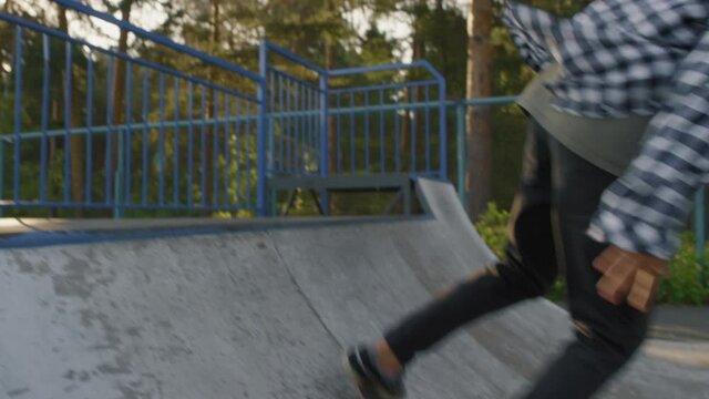 Slowmo tracking shot of young men skating on ramp in skatepark