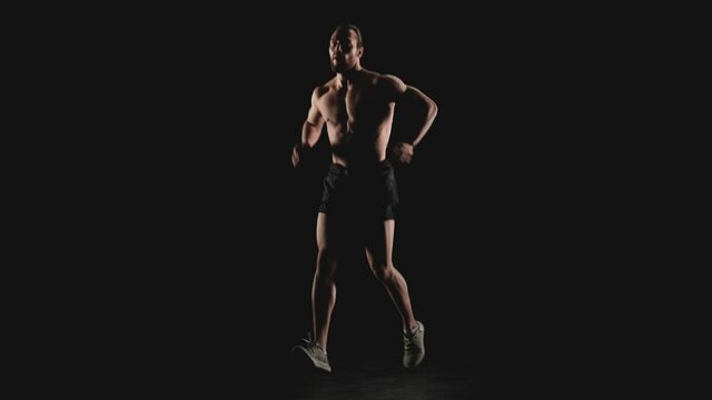 Athletic man does physical exercises on a black background. Slow motion