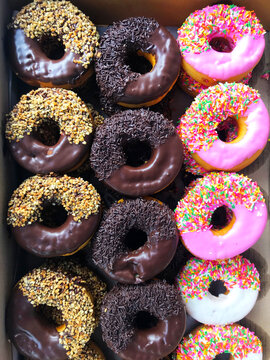 Overhead view of a box of assorted doughnuts with icing and sprinkles