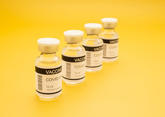 The covid-19 vaccine in glass bottles for prevention, immunization, and treatment from coronavirus infection on a yellow background. Space for text. Concept of medical and vaccine.