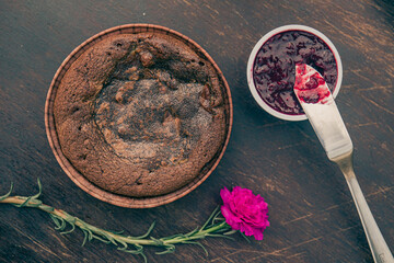 Chocolate cake and strawberry jam with a flower on a wooden table. Top view.