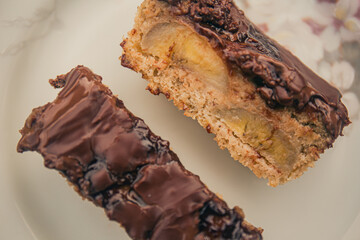 Banana cake with chocolate sauce on the top on a white plate. Top view.