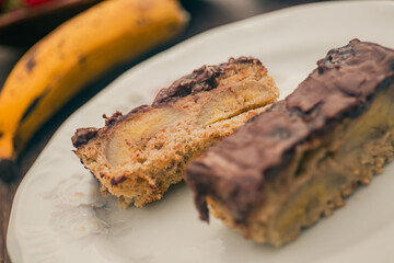 Banana cake with chocolate sauce on the top on a white plate.