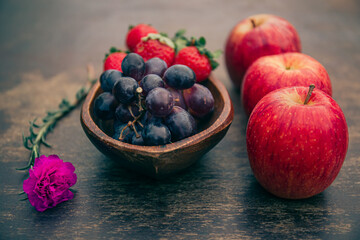 Delicious fruits on a wooden table. Strawberries, grapes and apples. 