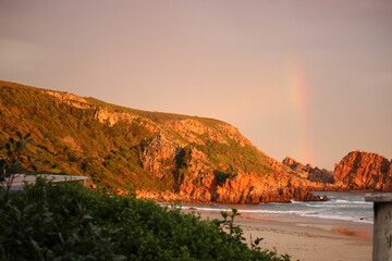 Rocky cliffs at sunset or sunrise with sea and rainbow