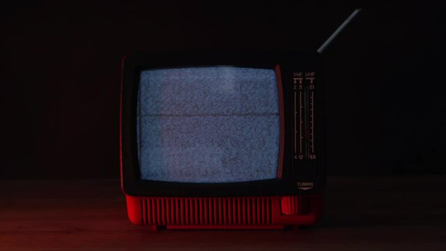 Red vintage television in a dark room. Bad TV signal transmission with noise and static