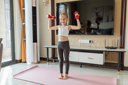 Little girl in sport clothing exercising at home. Online training during coronavirus covid-19 quarantine. Stay fit and safe during pandemic lockdown. Sport, fitness, healthy concept