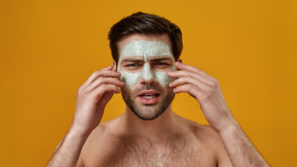 Obraz premium Man applying cleansing face mask to his face