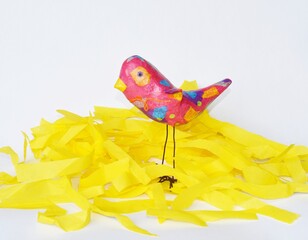Abstract bird sculpture art in yellow nest on white background