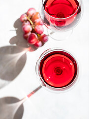 Red wine in a glass on a light concrete background in the rays of the sun.